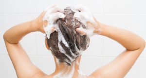 31287909 - woman washing her hair on white tiles background.