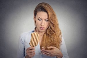 35516079 - portrait upset woman combing surprised she is losing hair, receding hairline. face expression emotion